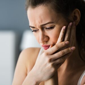Lady holding her jaw in pain