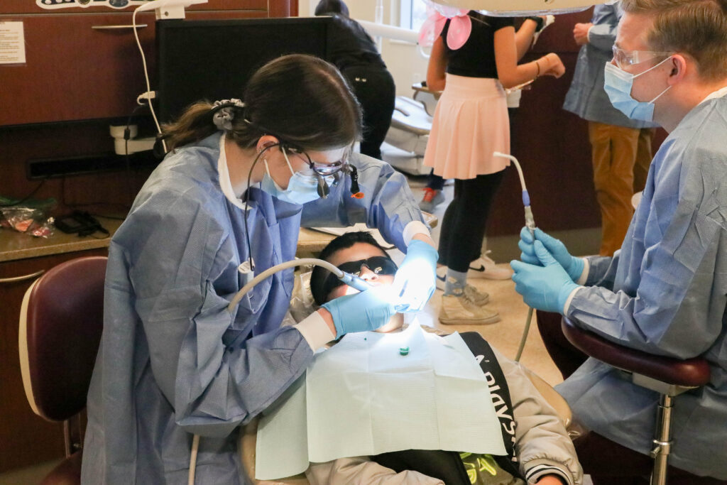 Dentists working on a child at Roseman Dental's Give Kids a Smile® event