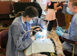 Dentists working on a child at Roseman Dental's Give Kids a Smile® event