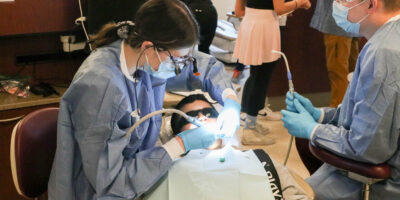 Dentists working on a child at Roseman Dental's Give Kids a Smile® event