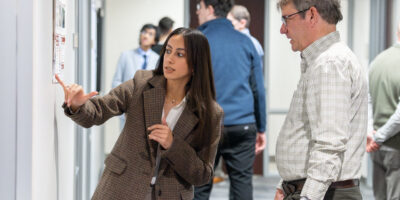 Student researcher points at poster