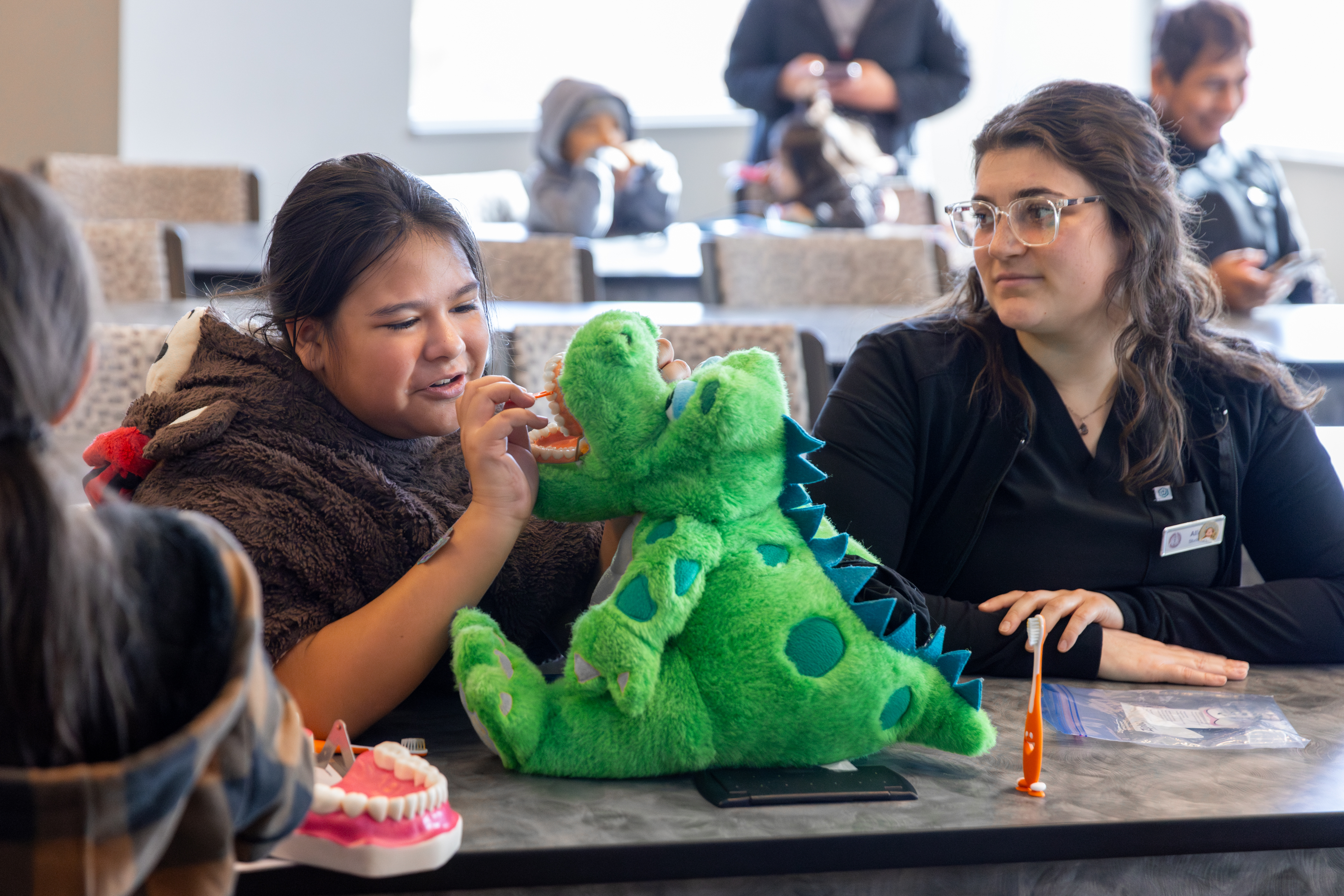 Young girl practices brushing technique on a stuffed animal during Roseman's annual Give Kids a Smile event.