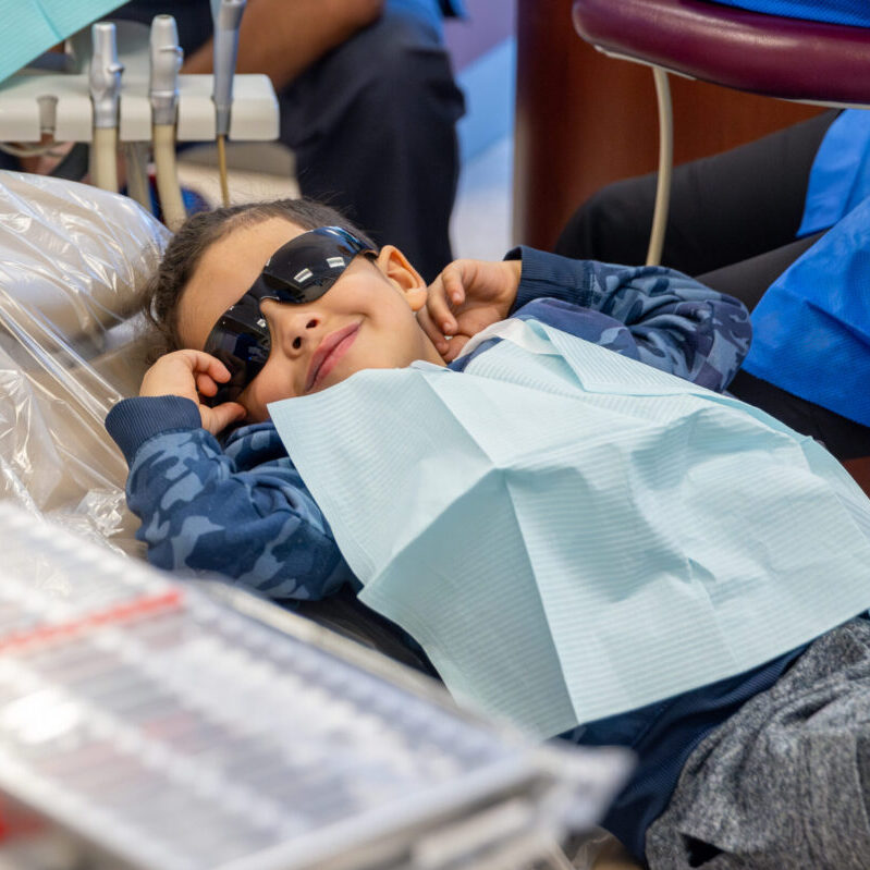 Young boy smiles broadly during oral health screening at Roseman's annual Give Kids a Smile event.