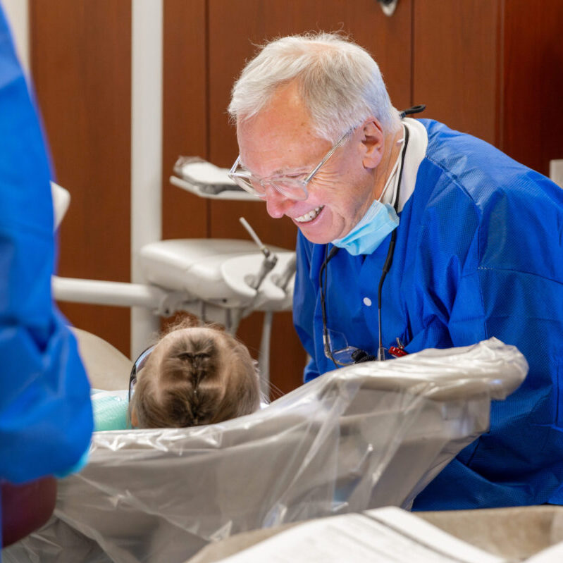 Dentist grins while providing dental care to a young patient at Roseman's annual Give Kids a Smile event.