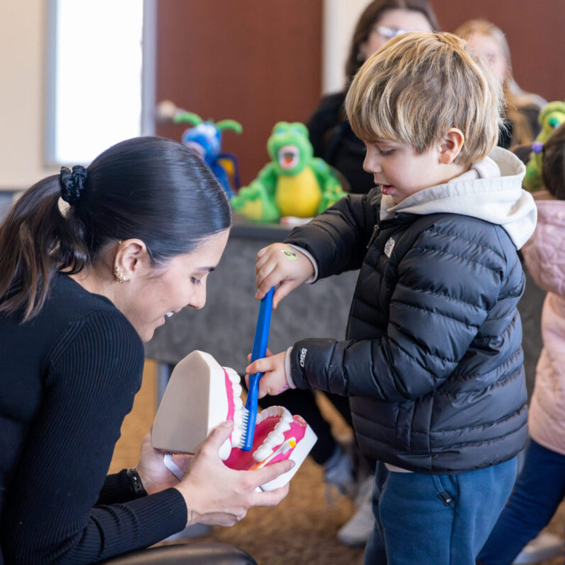 Young boy practices brushing a large set of teeth during Roseman's annual Give Kids a Smile event.