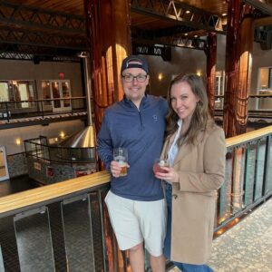 Dr. Kimberly Veltman and her spouse pose together at a distillery.