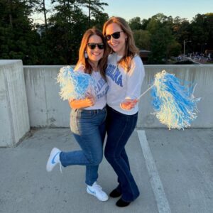 Dr. Kimberly Veltman and a friend cheer on the North Carolina Tar Heels with pom poms.