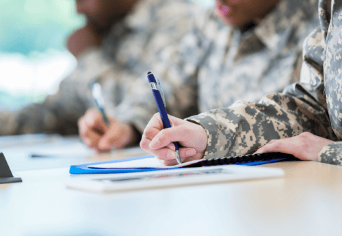 Person in military outfit writing on paper